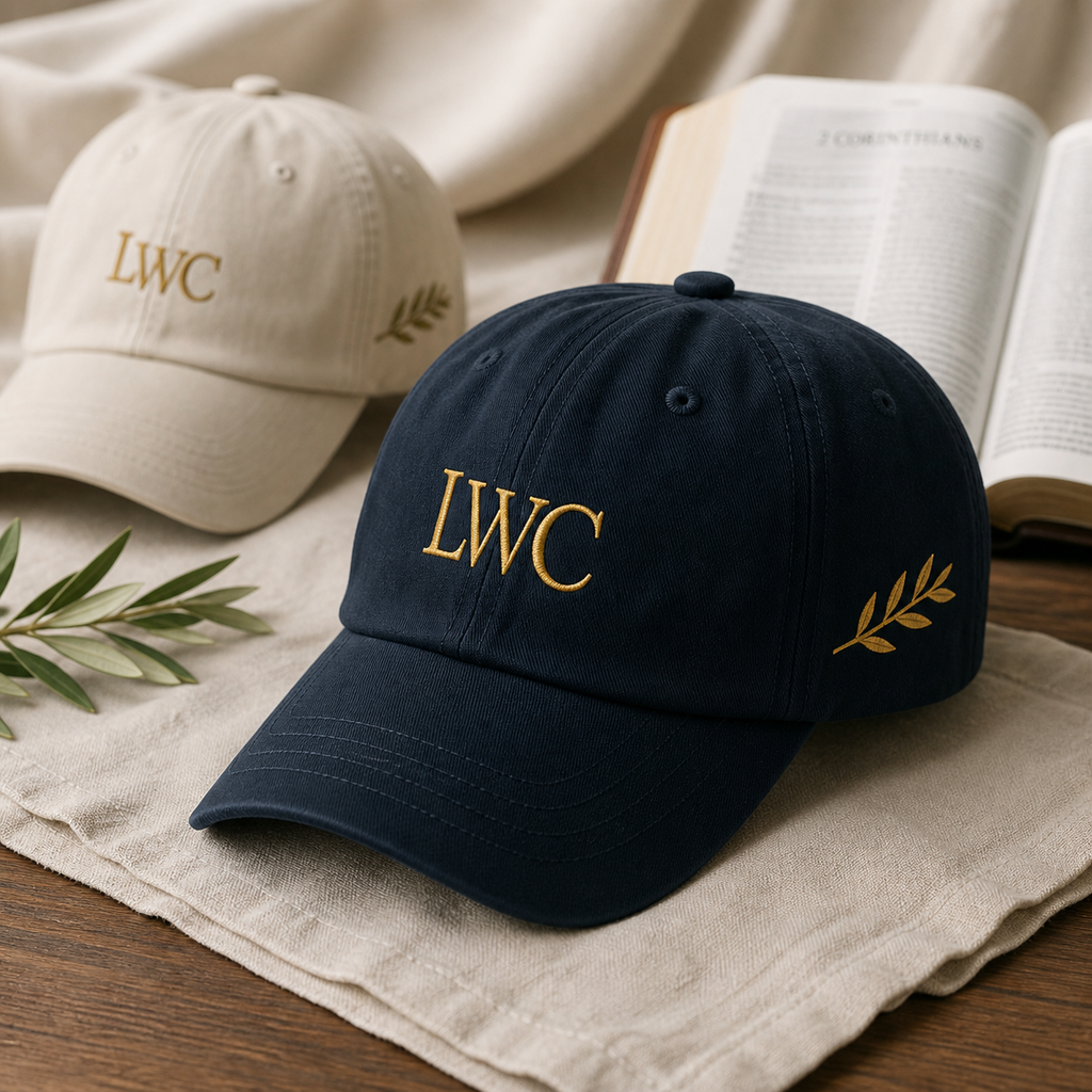 LWC Walk by Faith embroidered dad cap in navy with enlarged LWC monogram and clean olive branch beside a Bible.