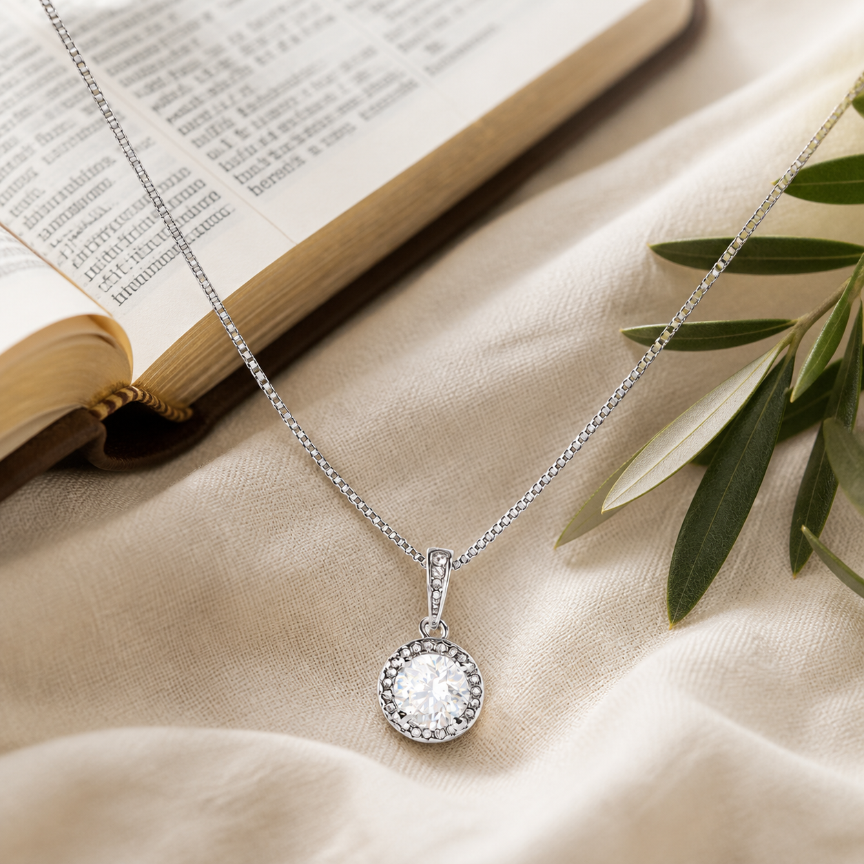 LWC Eternal Hope Necklace shown on linen beside an open Bible and olive branch.