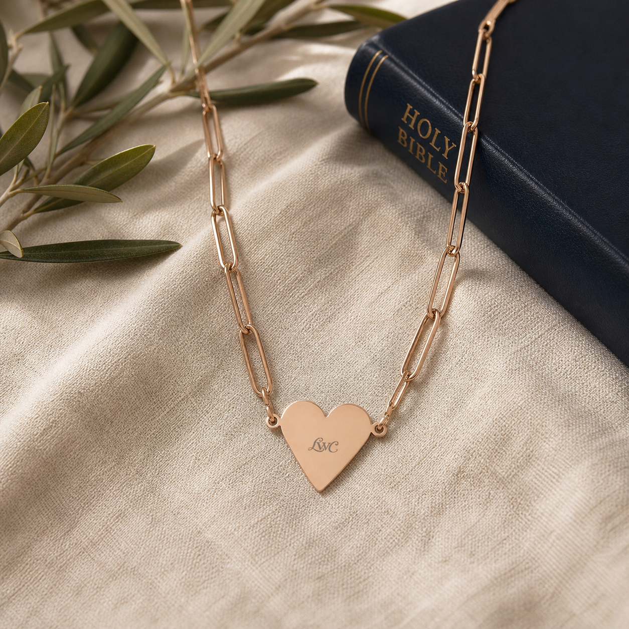LWC Paperclip Heart Necklace shown on linen beside a navy Bible and olive branch.